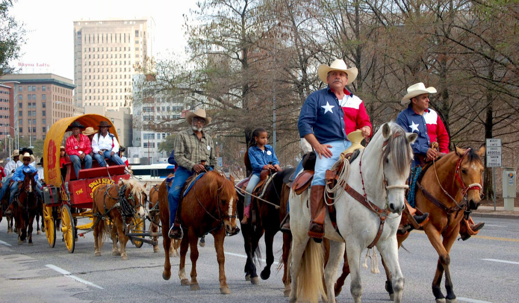 People riding horses through a Downtown street wearing Texas flag shirts