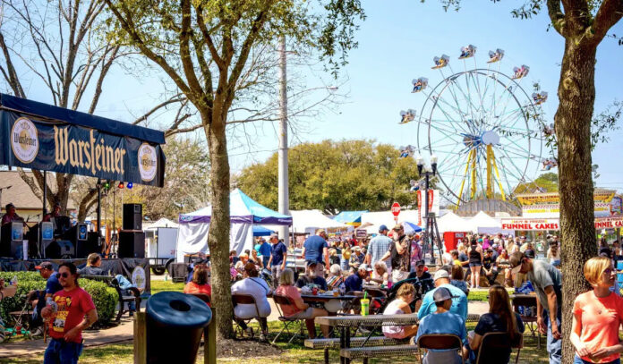 An outdoor carnival with festival goers eating and a Ferris Wheel in the background