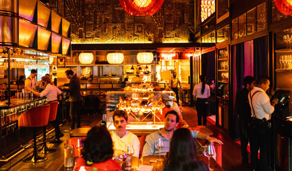 Interior of a red and gold-lit restaurant with people sitting at tables