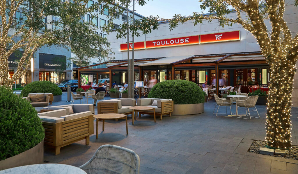 Exterior of Toulouse with outdoor seating and light-wrapped trees