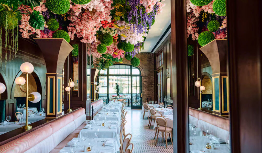 A dining room with extravagant bouquets of flowers hanging from the ceiling