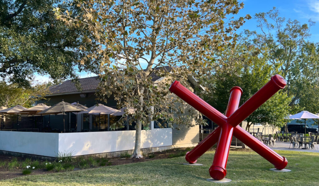 Exterior of Bistro Menil's patio with a red sculpture next to it