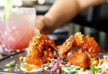Where to Happy Hour in the Museum District A plate of fried finger foods and a hand holding a pink and white drink in the background