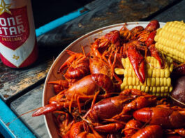 A plate of crawfish with corn and a bottle of Lone Star