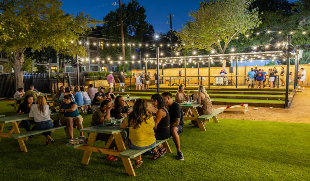 An outdoor bar area under string lights at night with bocce ball courts