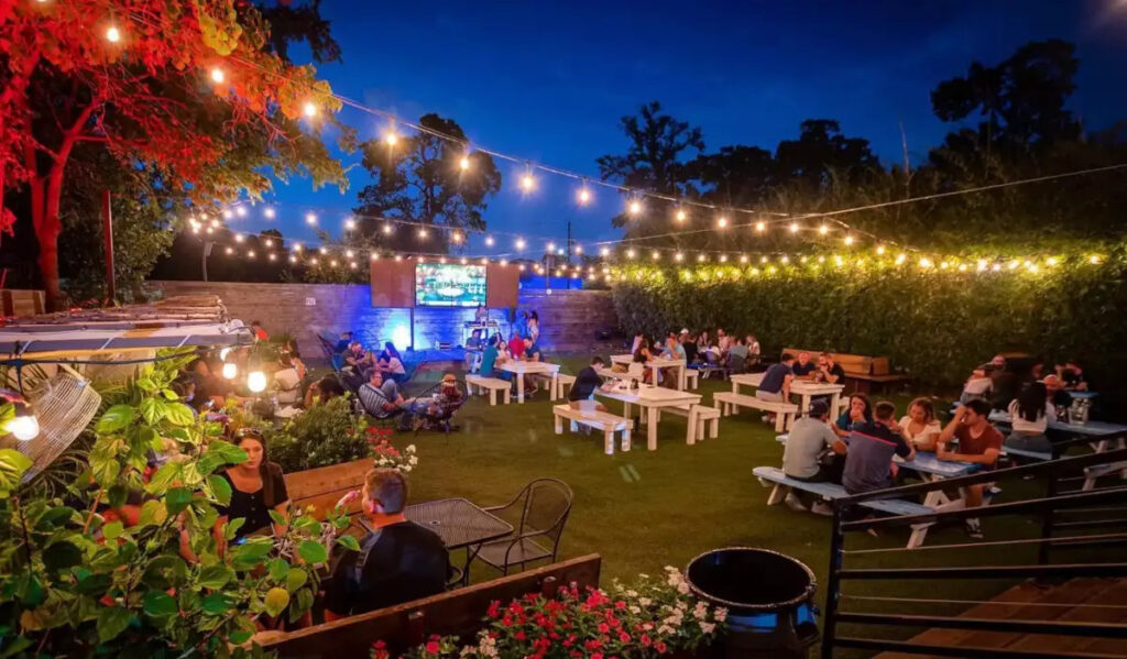 An outdoor patio space at night with a string of lights overhead