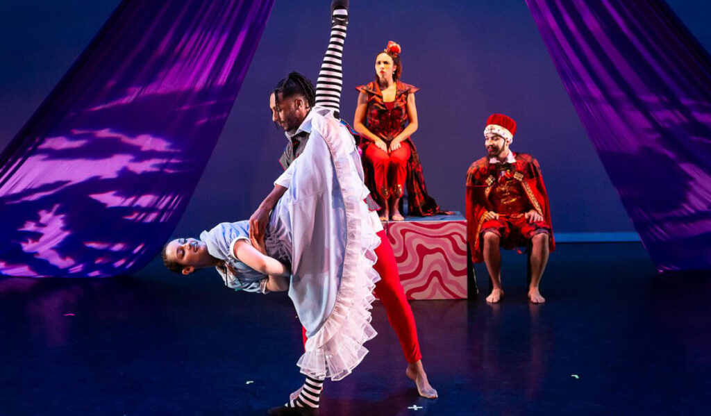 A dancer in Alice costume stretches a leg above her head