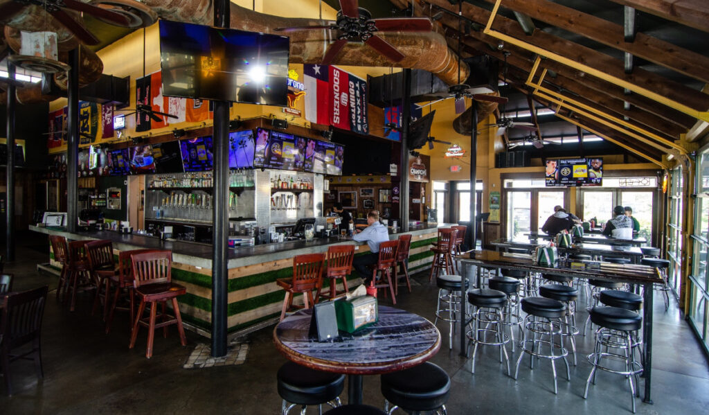 A bar area with TVs and stool seating