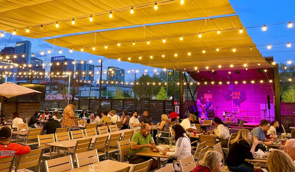 An outdoor patio with stage and the Downtown Houston skyline in the distance