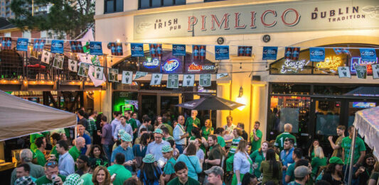 A crowd of green-clothed people outside of a pub