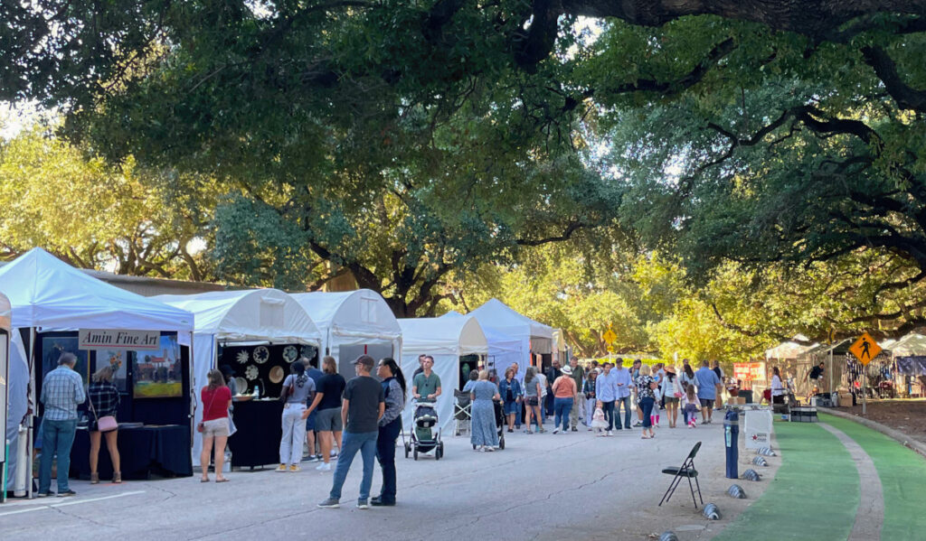 An outdoor art market underneath a canopy of oak trees