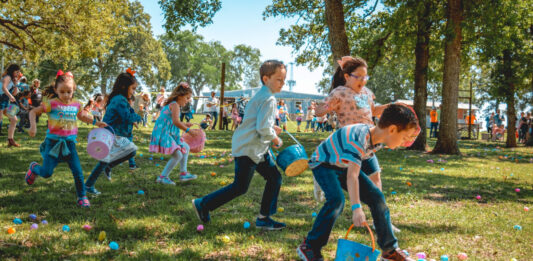 Kids run through grass while stooping to pick up Easter Eggs