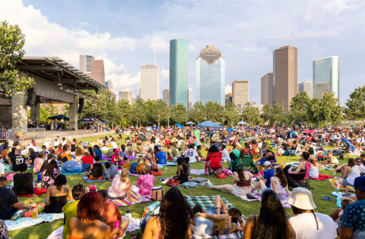 A crowd of people on blankets and chairs with the Downtown Houston skyline