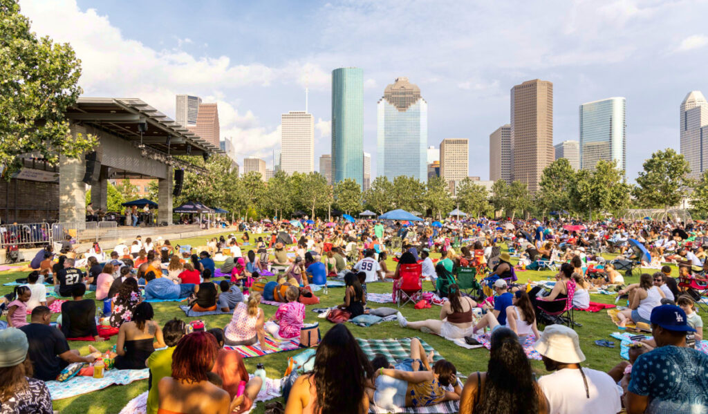 A crowd of people on blankets and chairs with the Downtown Houston skyline