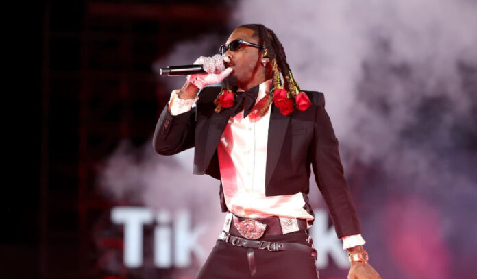 Rapper Offset performing on stage with roses in his hair