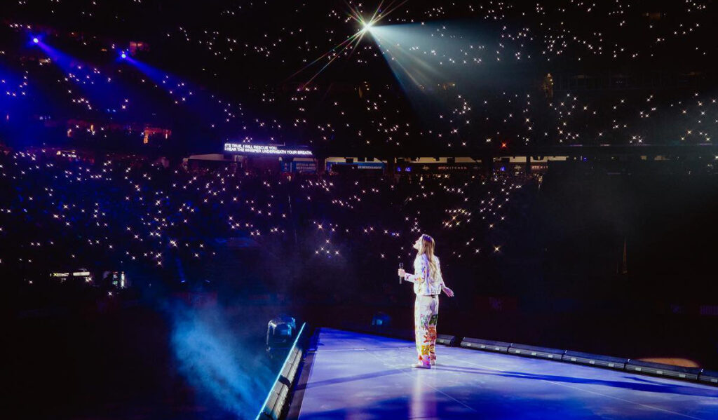 A performer facing a crowd with hundreds of small white lights