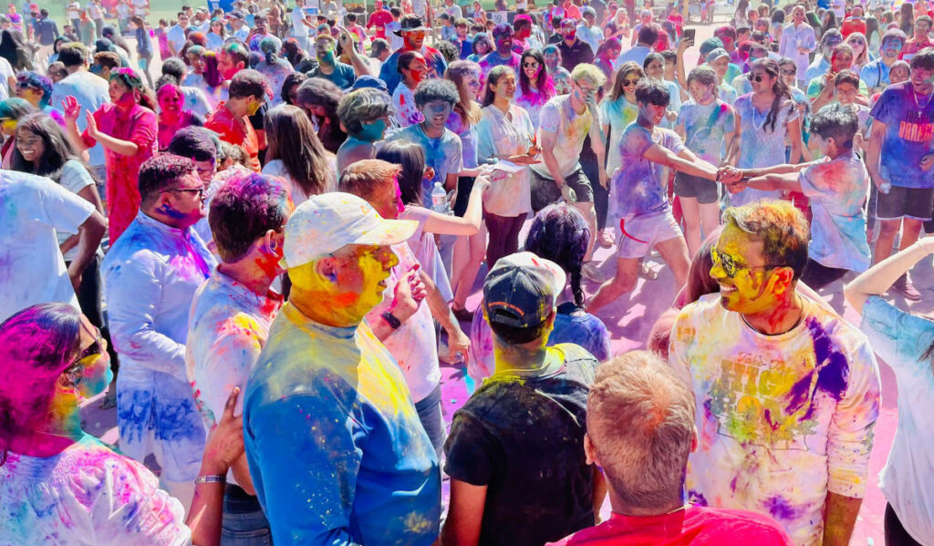 A crowd of people splattered with brightly colored pigment