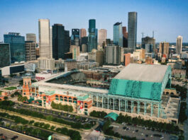 An aerial view of Minute Maid Park with the roof open and Downtown skyscrapers in the background