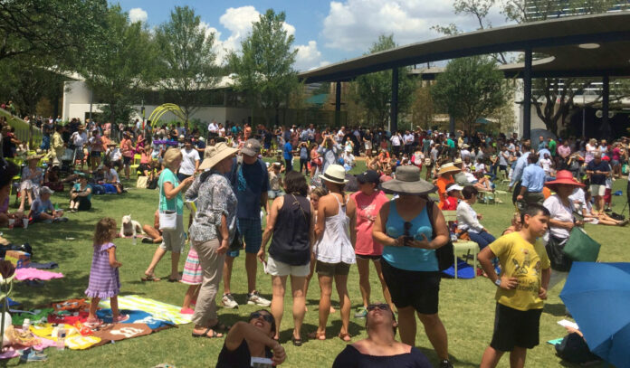 A busy park space with people looking to the sky