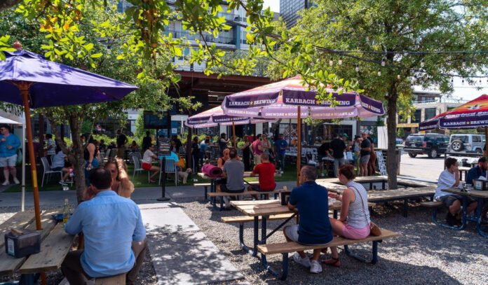 A shaded outdoor patio filled with patrons during the daytime