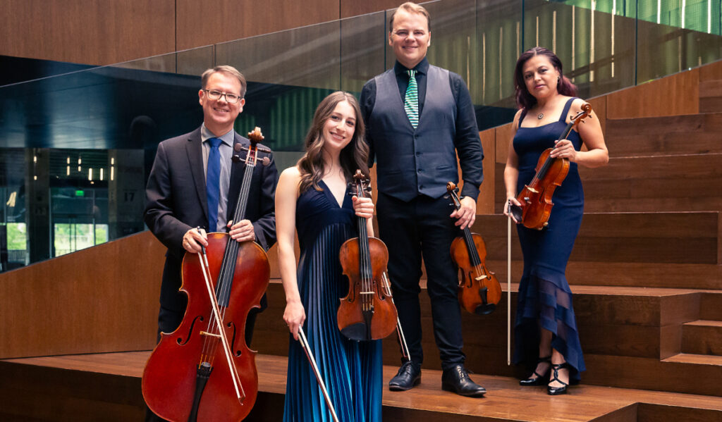 Four members of a quartet stand with instruments in formal wear