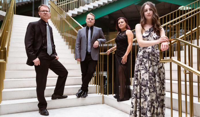 Two people in suits and two people in dresses standing on a white staircase