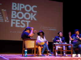 Four panelists on a stage in discussion with a projection of "BIPOC Book Fest" behind them