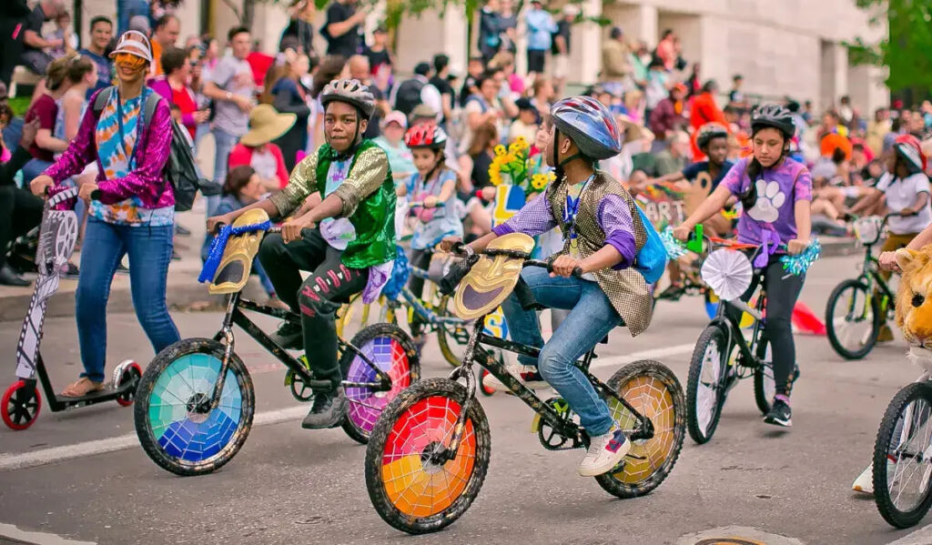 Kids ride bikes that have been decorated with colorful panels