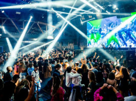 A nightclub interior with beams of white light and a crowd of people