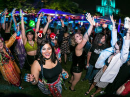 Party goers dance and raise their arms