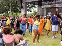 Lines of people dancing on a lawn next to a concert stage