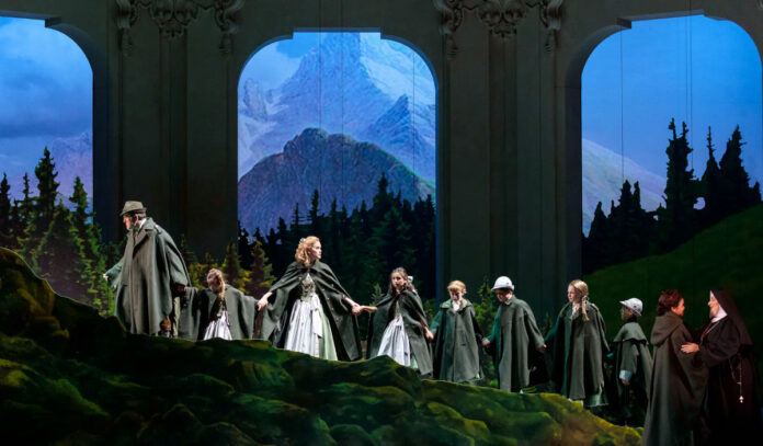 A set piece with a man and woman leading children up a hill with mountain vistas in the background