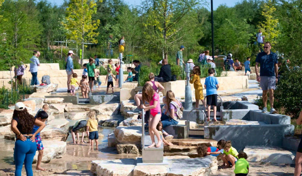 Kids and adults climbing on rock structures with water features