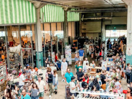 A view of a bustling marketplace with booths and people walking through