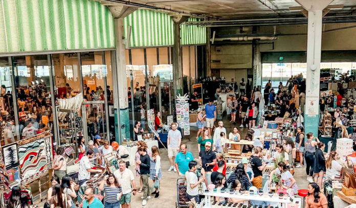 A view of a bustling marketplace with booths and people walking through