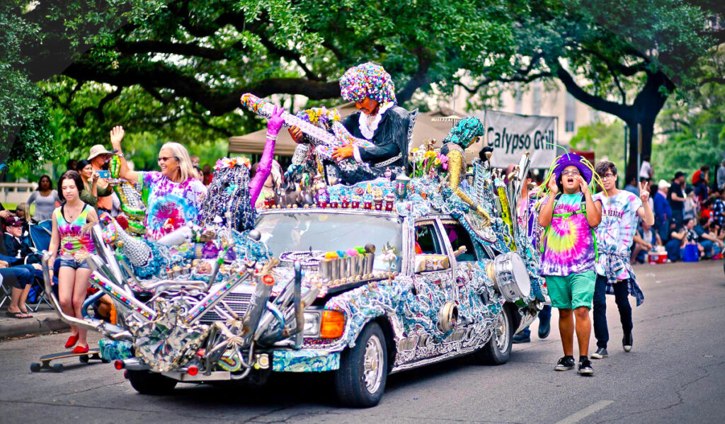 Kids in colorful clothing and hats walk alongside a highly decorative art car