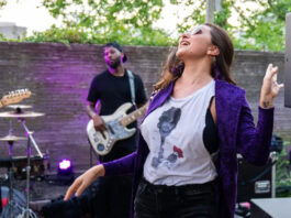A woman in a purple coat and Prince t-shirt dances to a band