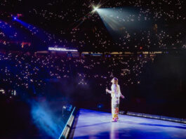 A performer facing a crowd with hundreds of small white lights