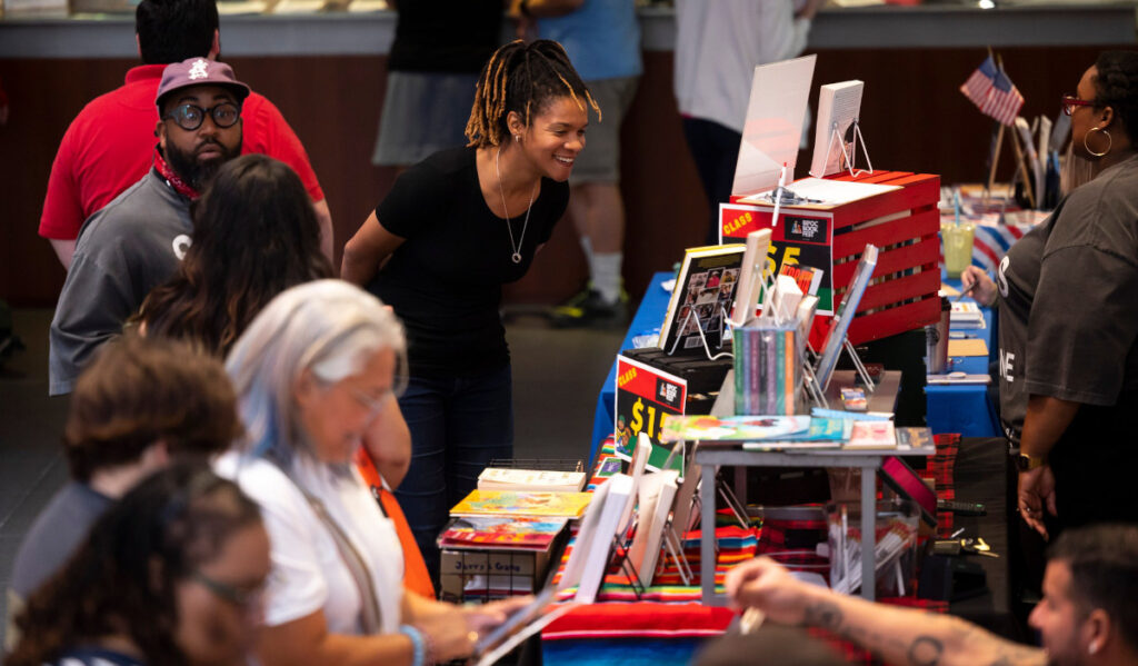 People buying books and browsing at booths at a book fair