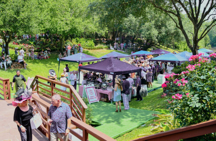 A sunny scene in a green lawn with vendors providing wine to patrons