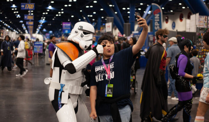 A child poses with a Star Wars stormtrooper for a selfie