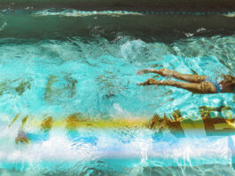 A woman swimming through a pool with a wake behind her