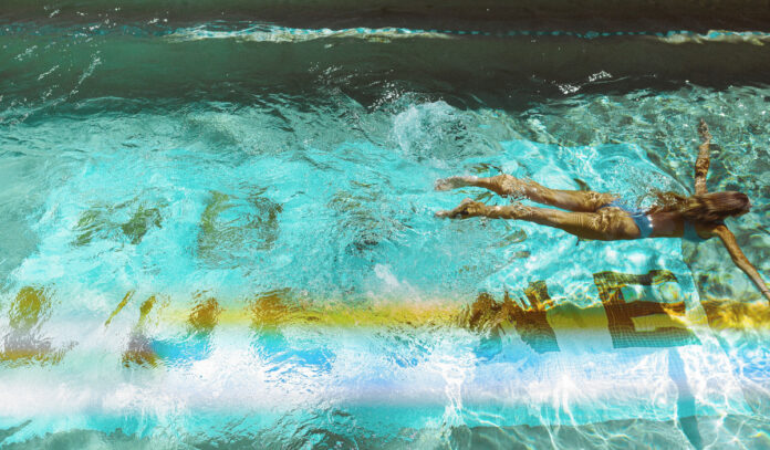 A woman swimming through a pool with a wake behind her