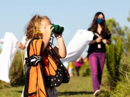 A child looking through binoculars while wearing butterfly clothing