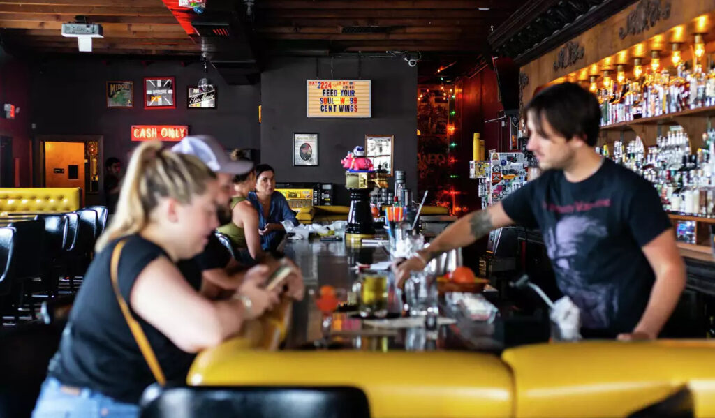 A view down a bar with thick yellow padding and patrons being served