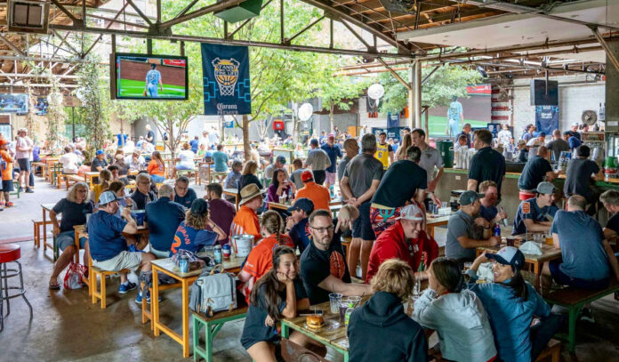 The outdoor patio of Pitch 25 filled with patrons watching Astros on TV