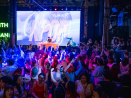 A club scene with crowds dancing and a DJ on stage