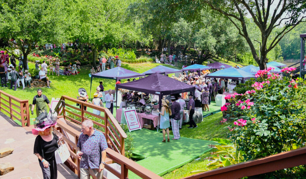 A sunny scene in a green lawn with vendors providing wine to patrons