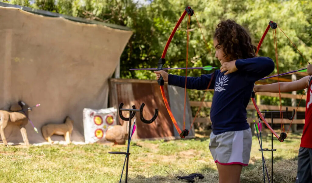 A child aims a bow and arrow