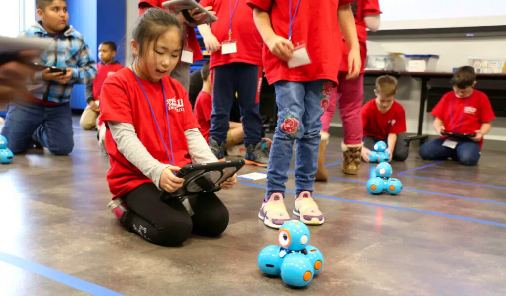 A child kneels while controlling a robot